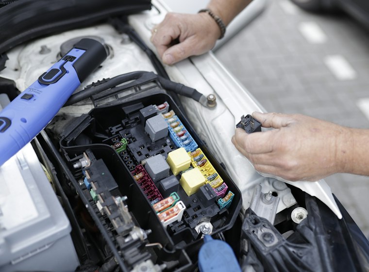 Mãos mexendo na caixa de fusíveis do carro